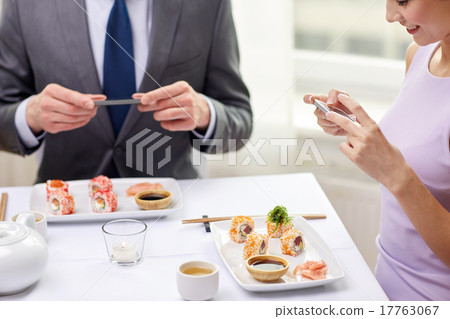 close up of couple with smartphones at restaurant 17763067