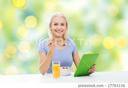 smiling woman with tablet pc eating breakfast smiling woman with tablet pc eating breakfast 17763136