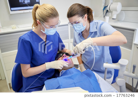 dentists treating male patient teeth at clinic 17763246