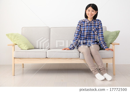 Woman sitting on sofa, with copy space 17772500