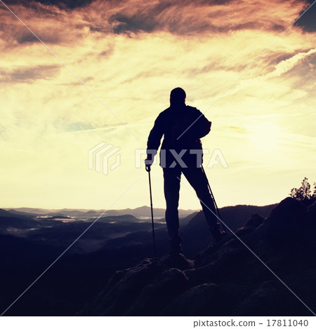 Silhouette of alone tourist with poles in hand.  17811040