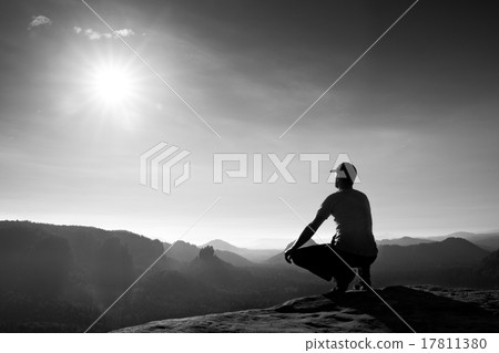 Runner sit  in squatting position on a rock 17811380