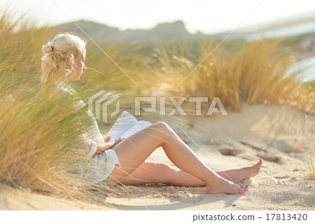 Woman enjoys reading on beautiful sandy beach. 17813420