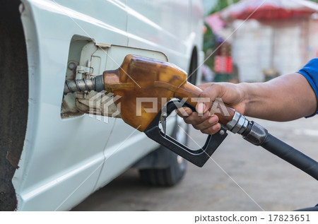 Hand hold Fuel nozzle to add fuel in car at filling station 17823651