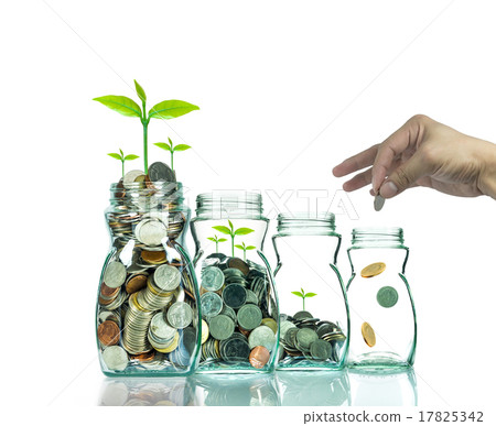 Hand putting mix coins and seed in clear bottle on white backgro Hand putting mix coins and seed in clear bottle on white backgro 17825342