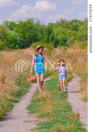 Girls sister in a field with a basket and flowers 17833834