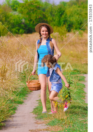 Girls sister in a field with a basket and flowers 17833843