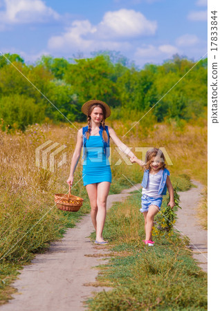 Girls sister in a field with a basket and flowers 17833844