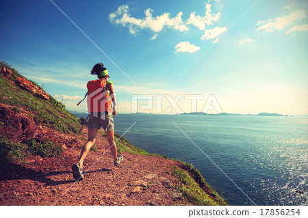 woman backpacker walking on seaside mountain trail woman backpacker walking on seaside mountain trail 17856254