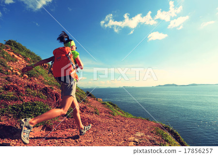 woman backpacker walking on seaside mountain trail woman backpacker walking on seaside mountain trail 17856257