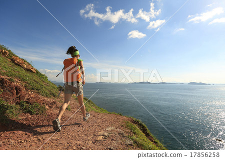 woman backpacker walking on seaside mountain trail woman backpacker walking on seaside mountain trail 17856258