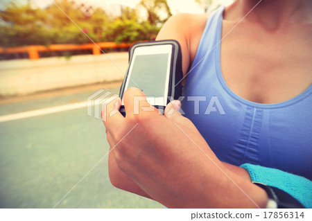 Runner athlete listening to music from smart phone 17856314
