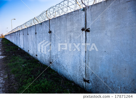 Concrete wall with barbed wire on top. 17871264