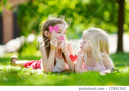 Adorable little girls playing with paper moustaches on a stick Adorable little girls playing with paper moustaches on a stick 17891342