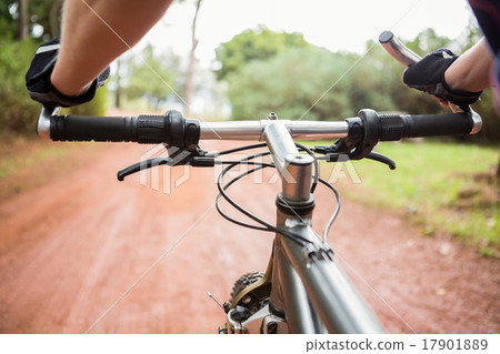 Woman mountain biking and holding handlebars Woman mountain biking and holding handlebars 17901889