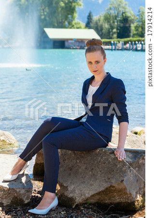 Young Businesswoman Sitting on Large Rock by Lake 17914214