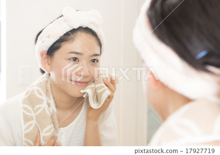 A woman wiping his face through a mirror 17927719