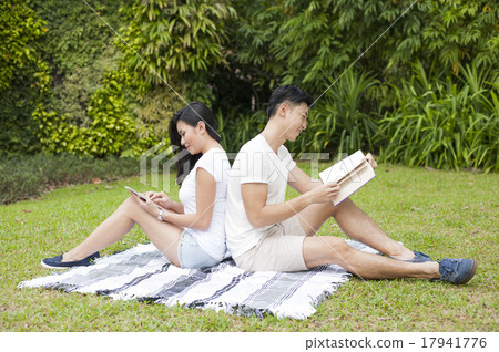 An Asian couple reading together in a park. An Asian couple reading together in a park. 17941776