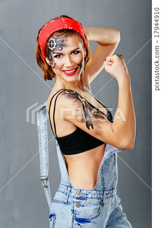 Girl mechanic with face art shows biceps. Girl mechanic with face art shows biceps. 17944910