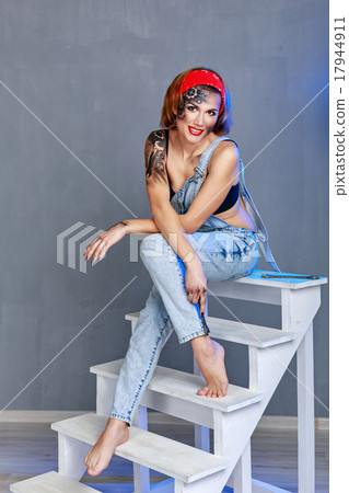 Girl mechanic with face art sitting on stepladder. 17944911