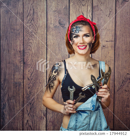 Girl mechanic with face art selects tools for work Girl mechanic with face art selects tools for work 17944912