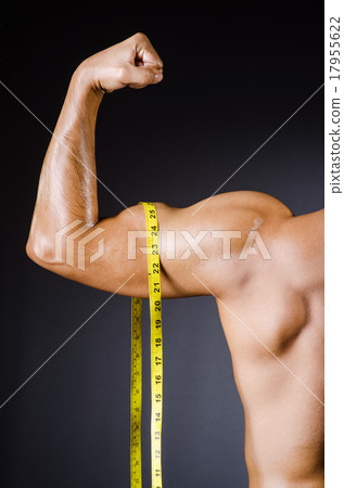 Muscular man measuring his muscles Muscular man measuring his muscles 17955622