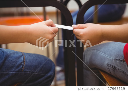 Pupil passing a note to a classmate Pupil passing a note to a classmate 17968519
