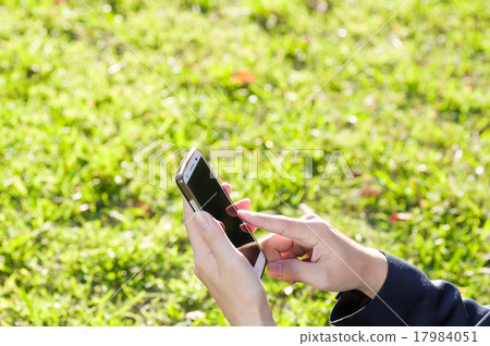 操作在充滿活力的草坪面孔的商人一個smartphone 17984051