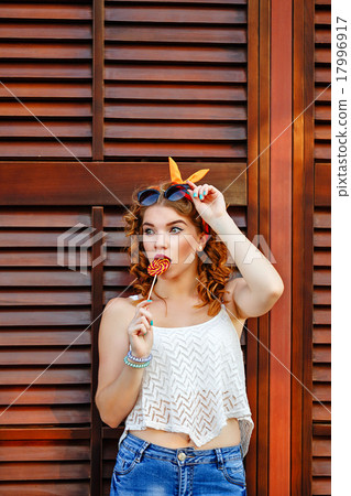 图库照片: pinup girl straightens sunglasses holding lollipop