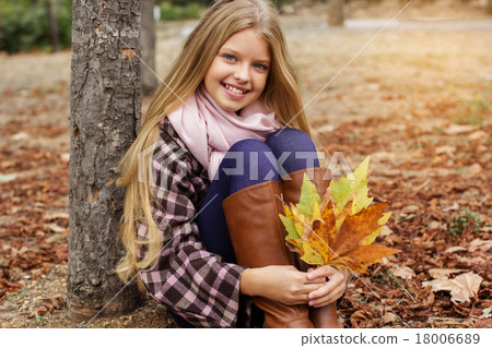 Pretty smiling girl with maple leaves in hands 18006689