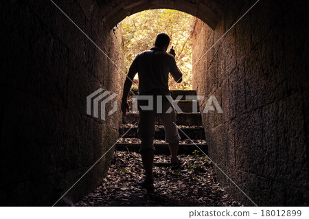 Young man with radio set in dark stone tunnel 18012899