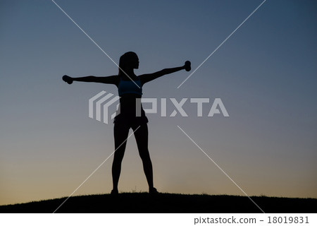 Girl shakes her muscles on the sunset background. 18019831