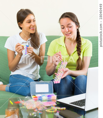 Girls braiding bracelets at home. 18040449