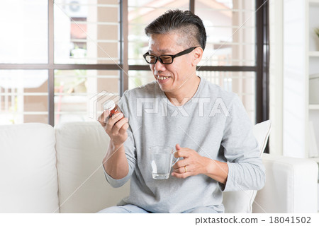 Asian man eating vitamins Asian man eating vitamins 18041502