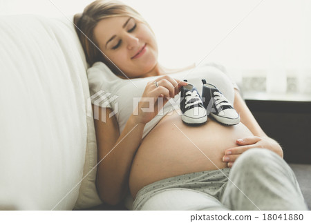 happy pregnant woman lying on sofa with baby boots happy pregnant woman lying on sofa with baby boots 18041880