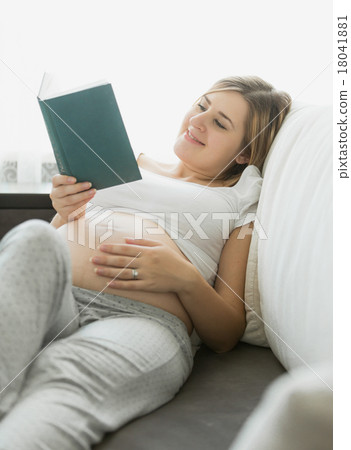happy pregnant woman reading book on sofa happy pregnant woman reading book on sofa 18041881