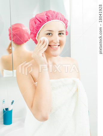 smiling woman using face cream after shower smiling woman using face cream after shower 18041928