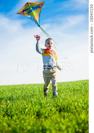 Young boy playing with his kite in a green field. Young boy playing with his kite in a green field. 18043150