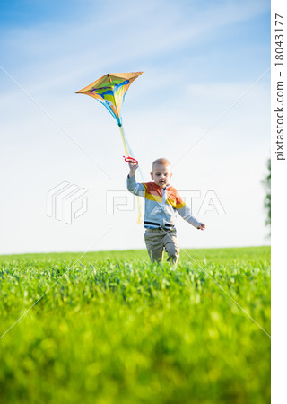 Young boy playing with his kite in a green field. Young boy playing with his kite in a green field. 18043177