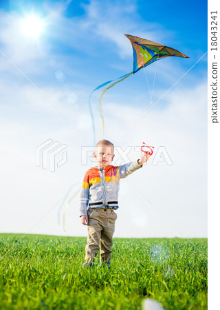 Young boy playing with his kite in a green field. Young boy playing with his kite in a green field. 18043241