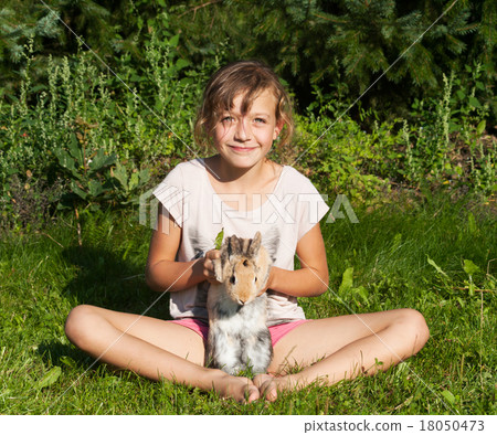 Girl with rabbit sitting on the meadow 18050473