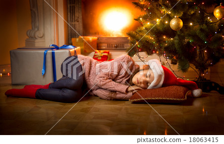 girl sleeping on floor under Christmas tree girl sleeping on floor under Christmas tree 18063415