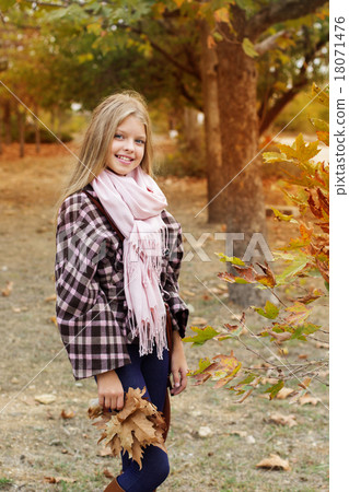 Cute girl is holding maple leaves in park Cute girl is holding maple leaves in park 18071476