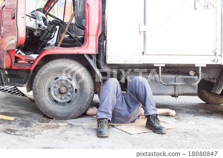 Mechanic under truck repairing dirty greasy engine Mechanic under truck repairing dirty greasy engine 18080847