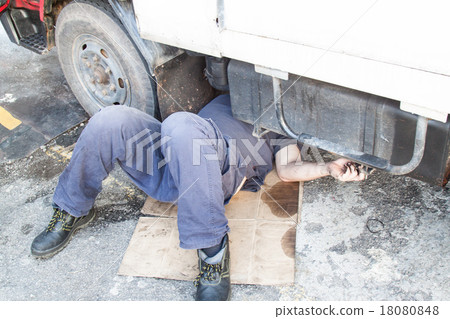Mechanic under truck repairing dirty greasy engine Mechanic under truck repairing dirty greasy engine 18080848