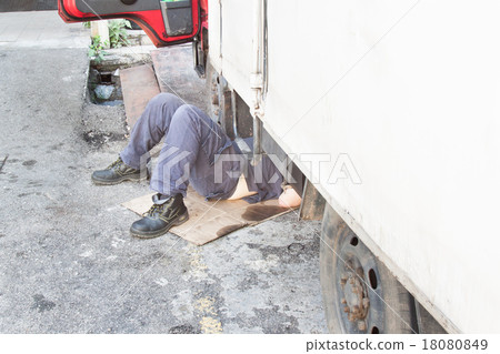 Mechanic under truck repairing dirty greasy engine Mechanic under truck repairing dirty greasy engine 18080849