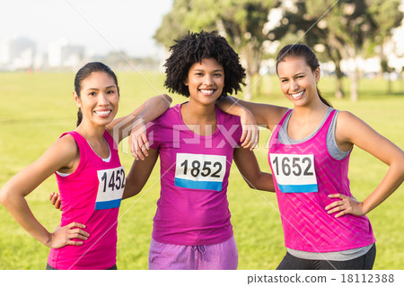 Three smiling runners supporting breast cancer marathon Three smiling runners supporting breast cancer marathon 18112388