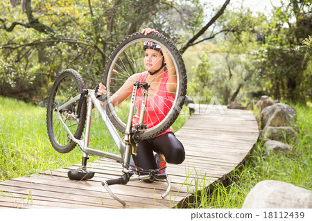 Blonde athlete checking her mountain bike 18112439