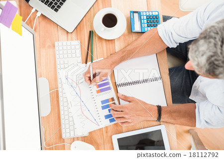 Casual businessman working on wooden desk Casual businessman working on wooden desk 18112792