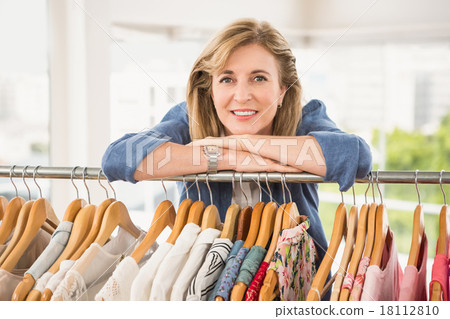 Smiling woman leaning on clothes rail Smiling woman leaning on clothes rail 18112810